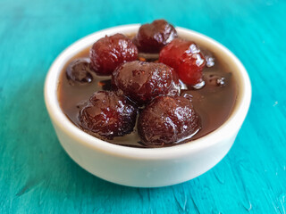 Delicious sweet grooselha with syrup on white bowl. Blue background.