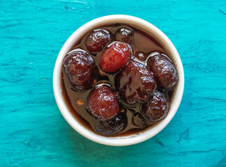 Delicious sweet grooselha with syrup on white bowl. Blue background.