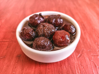 Delicious sweet grooselha with syrup on white bowl. Red background.