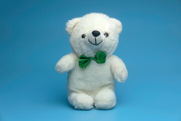 Selective focus of white teddy bear isolated on a blue background.