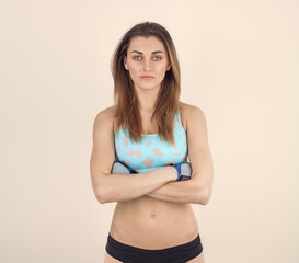 Portrait of a beautiful fitness woman with crossed arms. Looks straight into the frame.