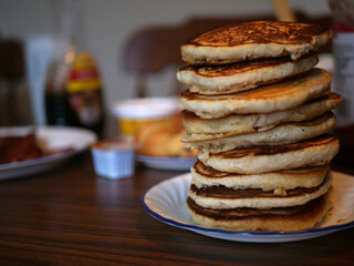 Stack of fluffy brown pancakes on a breakfast table in the morning