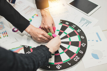 target and goal concept, business people put dart on board as meeting