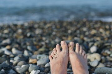 Two bare feet, next to each other, against the sea is out of focus.