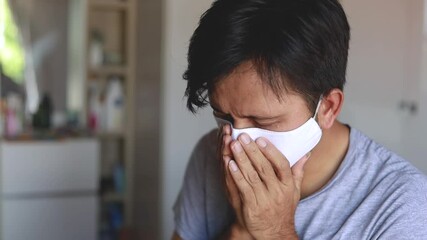 Young Asian man wearing face mask and coughing  - Powered by Adobe
