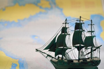 Vintage scale model of the historical tall ship and old white nautical chart close-up. Planning travel, sailing accessories, concept art, graphic resources, objects, collecting