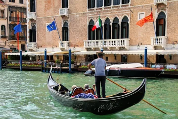Gondolier rowing gondola with tourists on Grand Canal in Venice, Italy