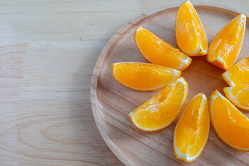 Oranges cut and served in a wooden plated on wooden table. Ready to eat or serve a juice. Natural food and drink concept