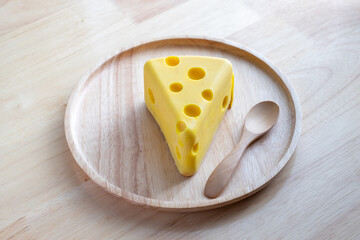 A cheese cake looks like real Swiss cheese in a wooden plate on wood table. Cheese cake concept