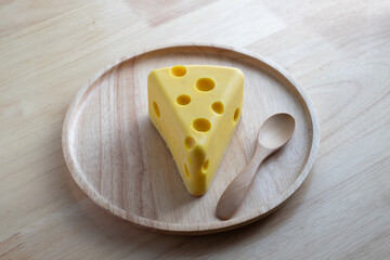 A cheese cake looks like real Swiss cheese in a wooden plate on wood table. Cheese cake concept