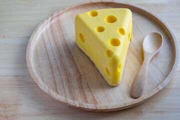 A cheese cake looks like real Swiss cheese in a wooden plate on wood table. Cheese cake concept