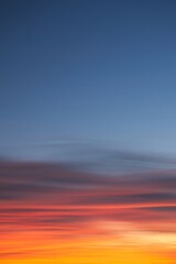 Intense, radiant orange cirrus clouds at dawn against a deep blue sky.