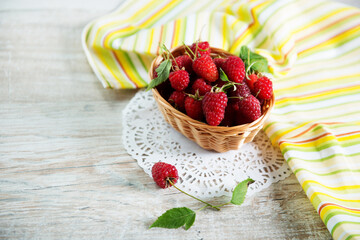 raspberries in a basket on a wooden table, a new crop