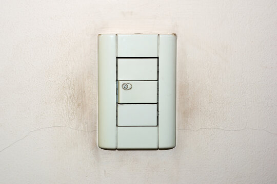 Dirty, old light switch on a cracked, weathered wall.