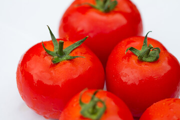 Details of a red tomato with green stipe and other blurry tomatoes in the background