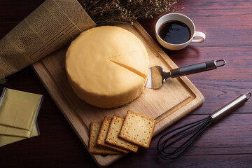 Emmental cheese cake with coffee and biscuit on wooden table.