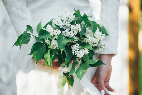a bouquet of white lilac in the hands of the bride