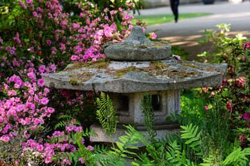 Fototapeta na wymiar Old stone lantern and blooming plants