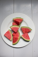 Cut water melon pieces on a white plate and white wooden floor, summer food