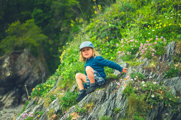 Naklejka na ściany i meble Little preschooler sitting on cliff