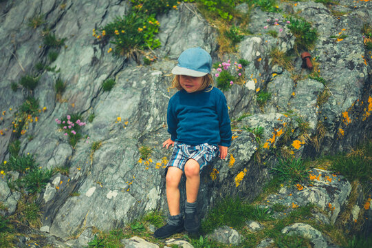 Preschooler boy sitting on a cliff