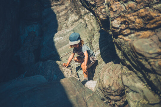 Preschooler boy climbing rocks in the summer