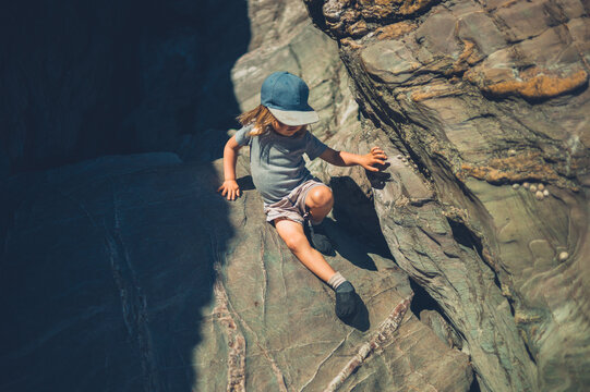 Preschooler boy climbing rocks in the summer
