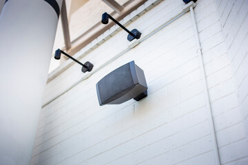 A view of an outdoor speaker mounted to the wall of a building.