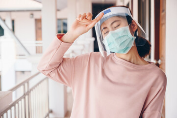 Fototapeta na wymiar Asian woman wearing mask and face shield before going outside her room for prevent and protection covid-19 virus disease.
