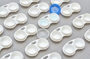lenses in a container on a gray background. a pattern of containers for lenses