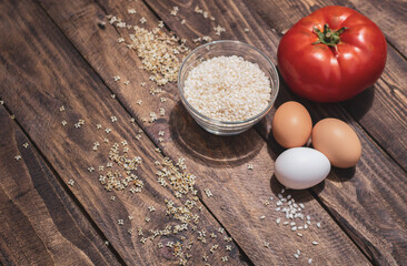 Cuban rice ingredients: tomato, rice and eggs on a wooden background