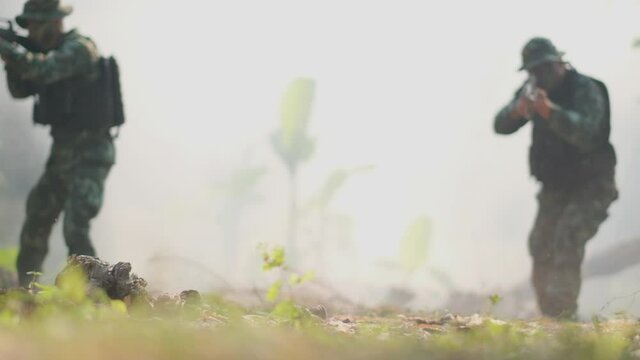 Soldiers point gun to different direction to fight with enemy and walk through fog for war fighting. Concept of practice of soldier for fighting and support for good management in war.