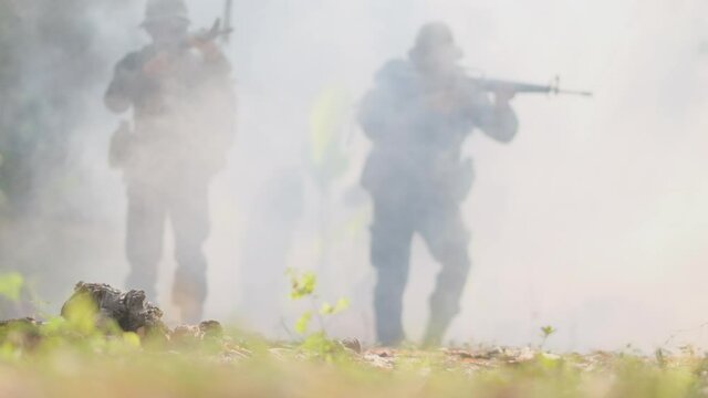 Group of soldier walk through fog from war fighting and they point gun to different direction to fight with enemy. Concept of practice of soldier for fighting and support for good management in war.