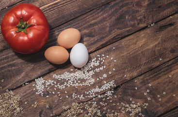 Cuban rice ingredients: tomato, rice and eggs on a wooden background