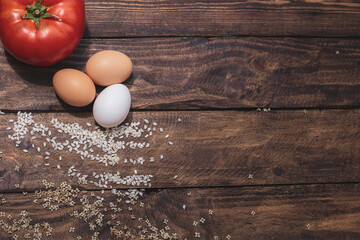 Cuban rice ingredients: tomato, rice and eggs on a wooden background