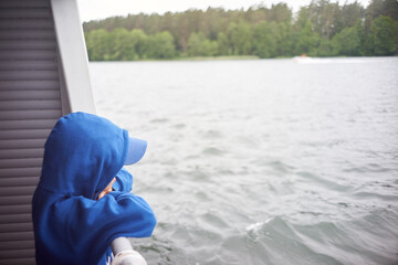 Caucasian kid observing water from the deck during travel by ship