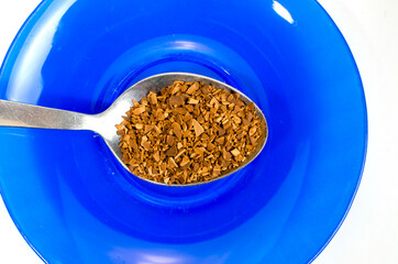 metal spoon with instant coffee on a blue saucer	
