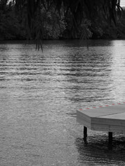 A simple pier over lake in black and white with abscence. There is a red white line visible on the edge of the wood structure