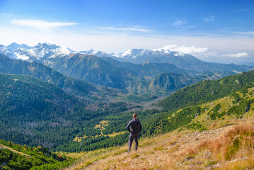 Fototapeta na wymiar Hiker on the mountain crest enjoying the view. A man tourist on the ridge, seeing the panorama. Central Europe.
