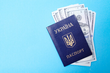 Ukrainian passport on a blue background. $ 100 dollars are inside the passport at different angles