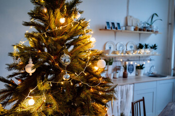 Christmas lights in the interior, Christmas tree with a garland, selective focus, blurred background, evening shooting, holiday atmosphere, picture with noise