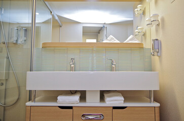 Clean and modern design bathroom with sink, shower, bath tub, towels and mirror and mosaic tiles in...