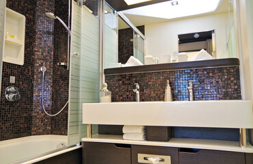 Spacious and luxurious classy bathroom of Suite category stateroom or cabin with brown mosaic tiles...