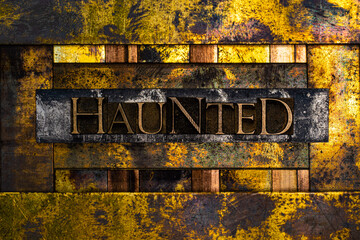 Haunted text formed with real authentic typeset letters on vintage textured silver grunge copper and gold background