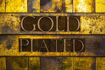 Gold Plated text formed with real authentic typeset letters on vintage textured silver grunge...