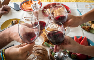 Group of family or friends toasting with a glass of red wine at home. Healthy food on the table. Four people together in happiness