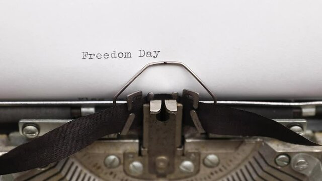 Typing a phrase Freedom Day on a vintage typewriter close-up. concept of freedom and fourth of July
