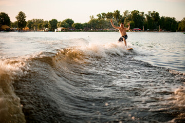 young man wakesurfer balancing on the wave