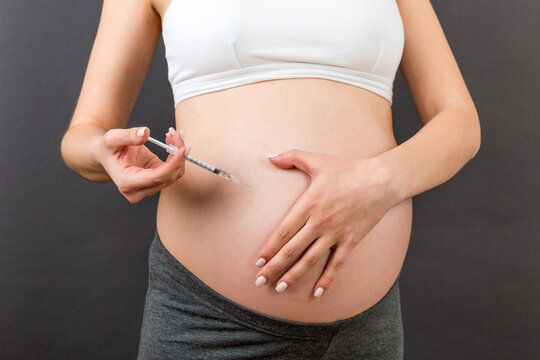 Cropped image of pregnant woman making insulin injection to control sugar level at colorful background with copy space. Healthcare concept