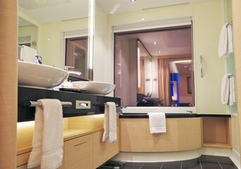 Clean and modern design bathroom with sink, shower, bath tub, towels and mirror and mosaic tiles in...